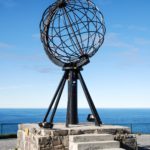 Nordkapkugel, dahinter das Europäische Nordmeer und blauer Himmel
