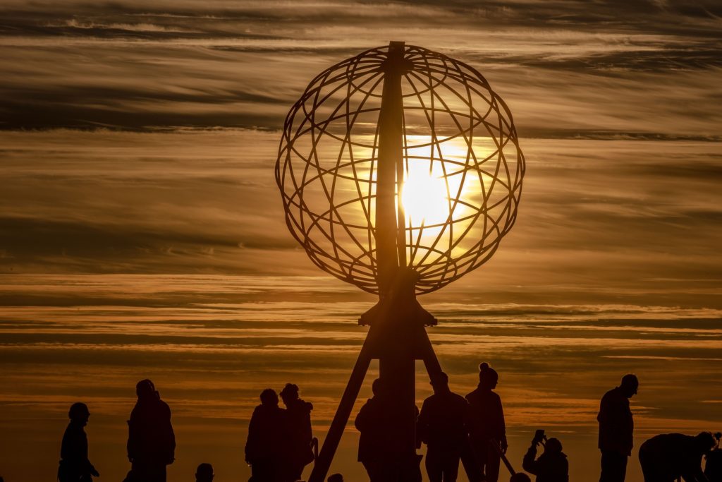 Skandinavien Nordeuropa Busreise Norwegen Menschen an der Nordkapkugel die Mitternachssonne im Hintergrund
