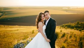 Hochzeitspaar im Sonnenlicht vor einem Feld