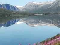 Blick auf spiegelklaren See mit norwegischem Gebirgszug im Hintergrund