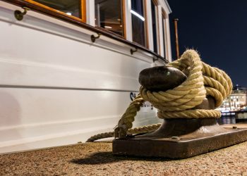 weißes Boot was mit einem Schiffstau am Anlieger fest ist